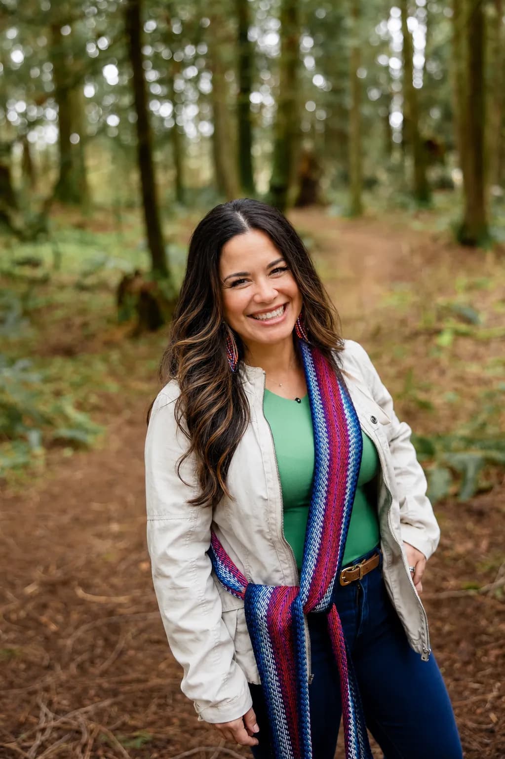 Michelle smiling in a forest, wearing a Métis sash