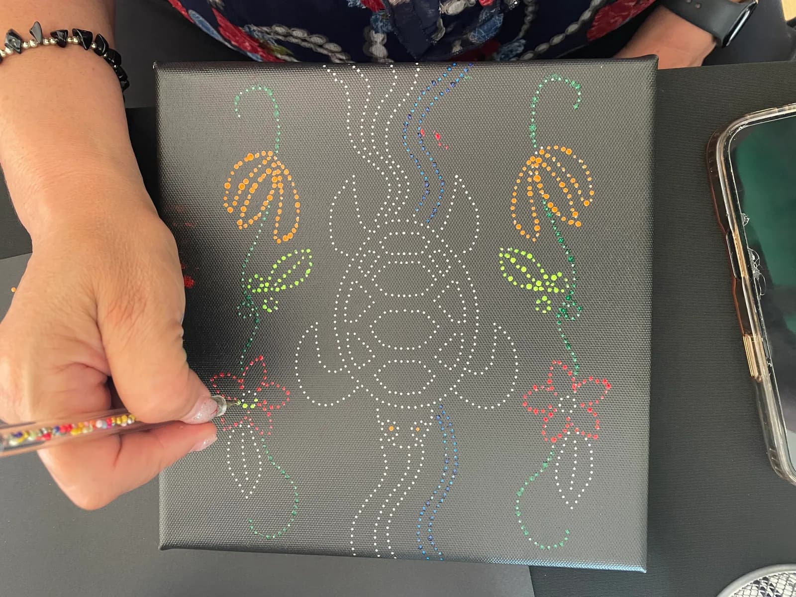 Hand dotting a canvas with a dotting tool